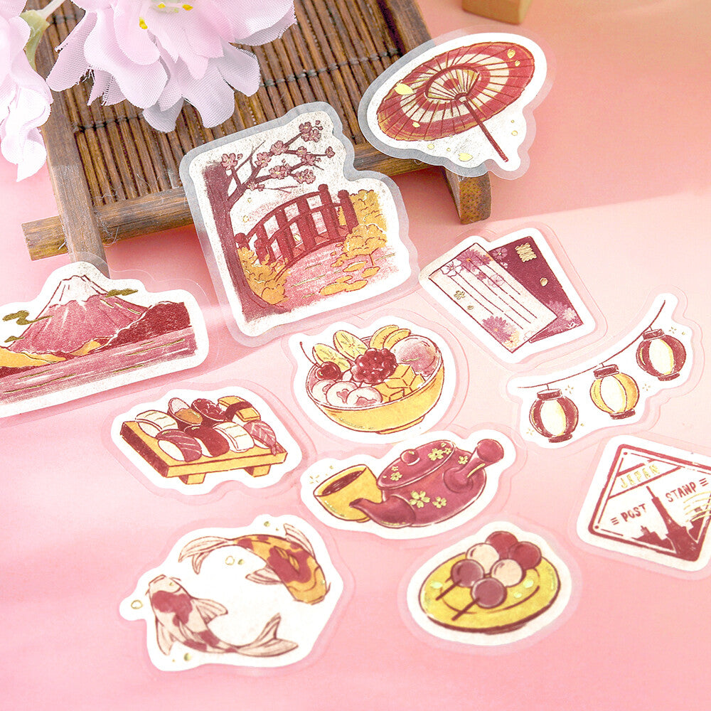 Close-up of BGM To Japan foil-stamped flake stickers with Mount Fuji, tea, sushi, lanterns and traditional Japanese motifs