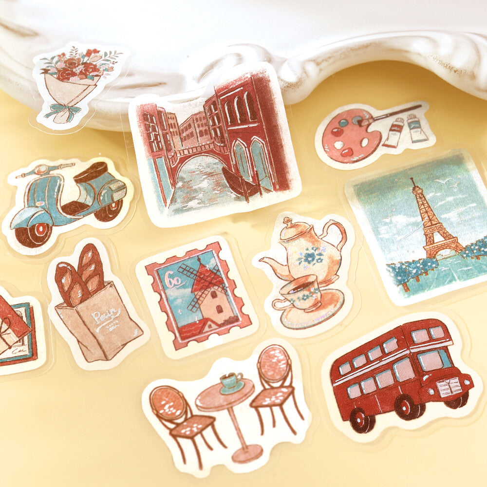 Close-up of BGM To the World foil-stamped flake stickers with European travel, café and art motifs