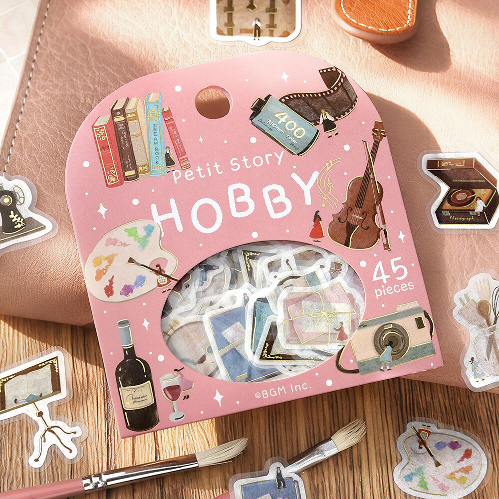 BGM Petit Story Hobby sticker package styled with hobby-themed flake stickers on a warm desk setting