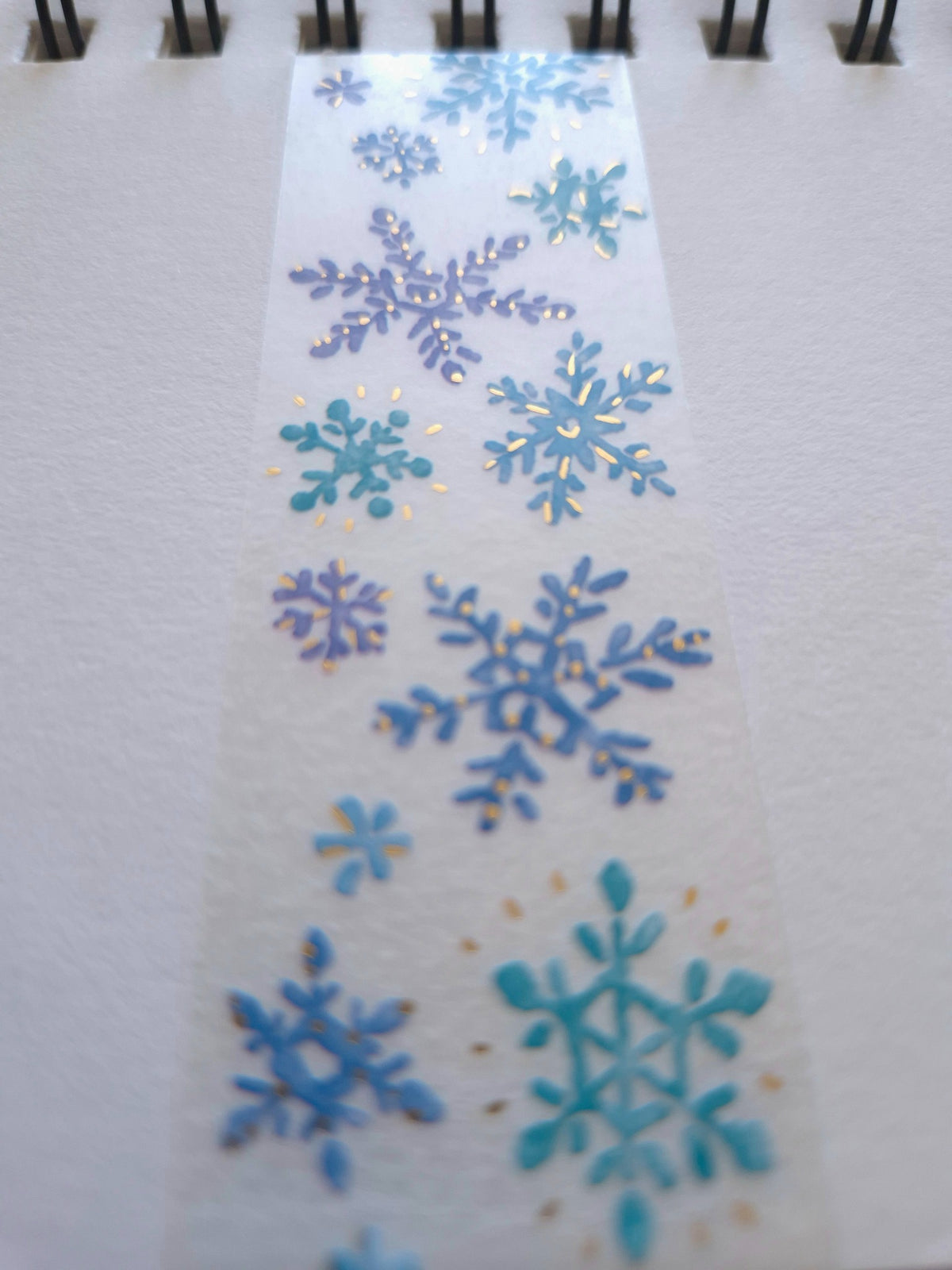 Close-up of Mind Wave Hokkori Life Kessho clear tape showing blue snow crystals with gold foil accents